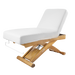 White massage table with wooden base on a black background