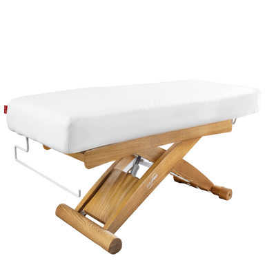 Wooden massage table with white cushion on a white background