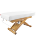 Wooden massage table with white cushion on a white background